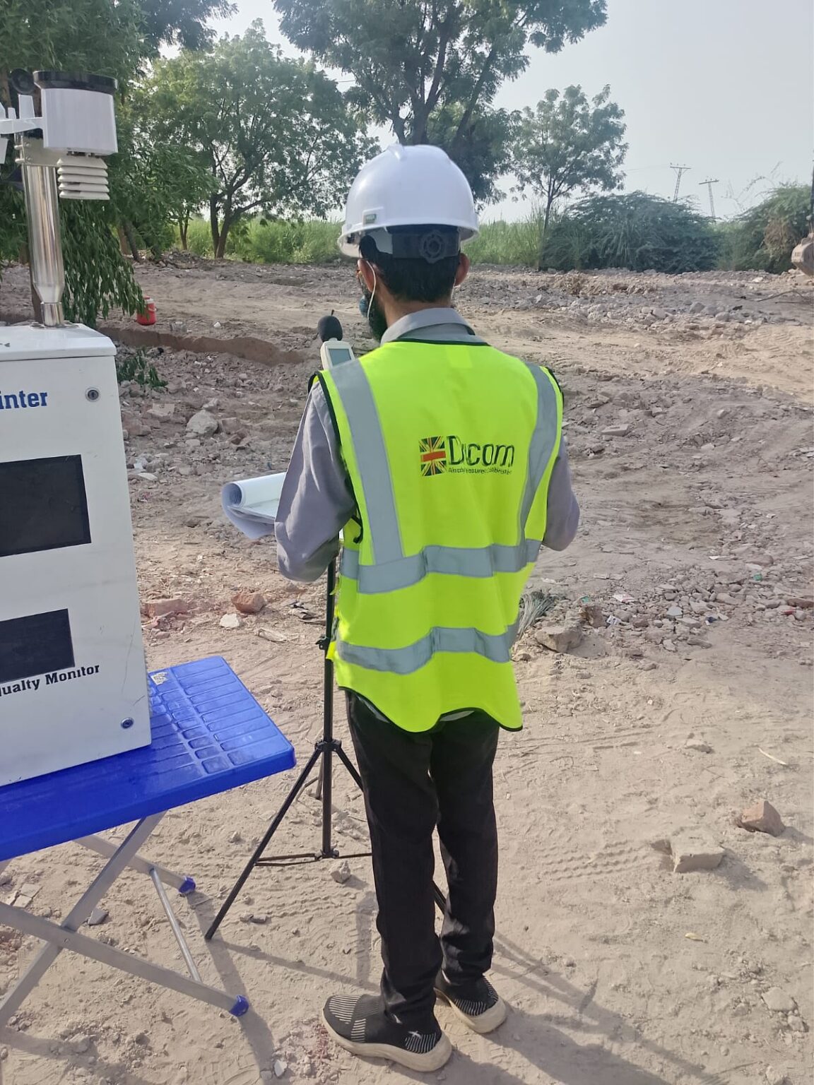 DUCOM environmental technician with air quality monitoring equipment at a project site